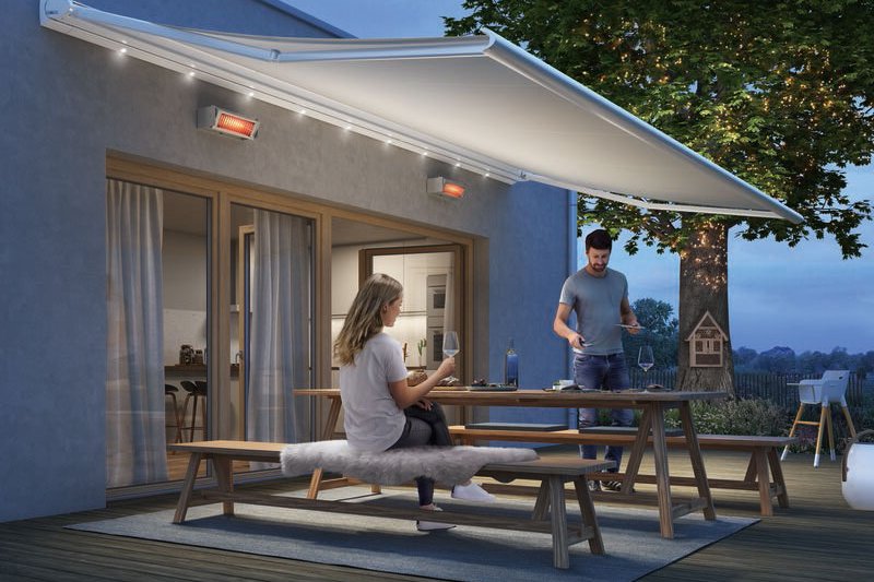 Een terras met een grote zonnescherm en een houten tafel, mensen genieten van de avond.