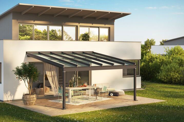 Moderne woning met een overkapping en terras in een groene omgeving onder een blauwe lucht. Moderne woning met een overkapping en terras in een groene omgeving onder een blauwe lucht.