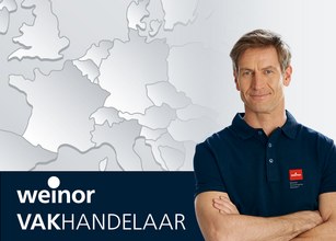 Man met kort haar en een donkerblauwe polo, staande voor een wereldkaart in grijstinten. 