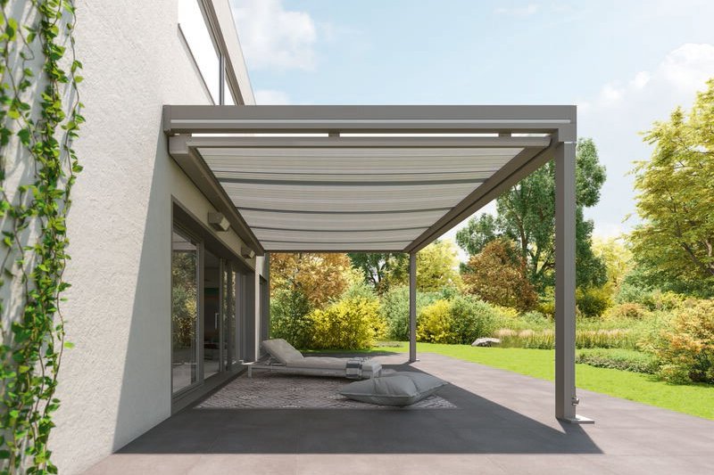 Moderne overkapping met glazen dak en zithoek in een groene tuin.