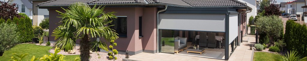 Een moderne woning met een overdekte terrasruimte en groene tuin.