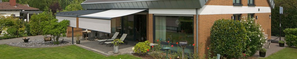 Een moderne woning met een overkapping, terrassensituatie en groen rondom.