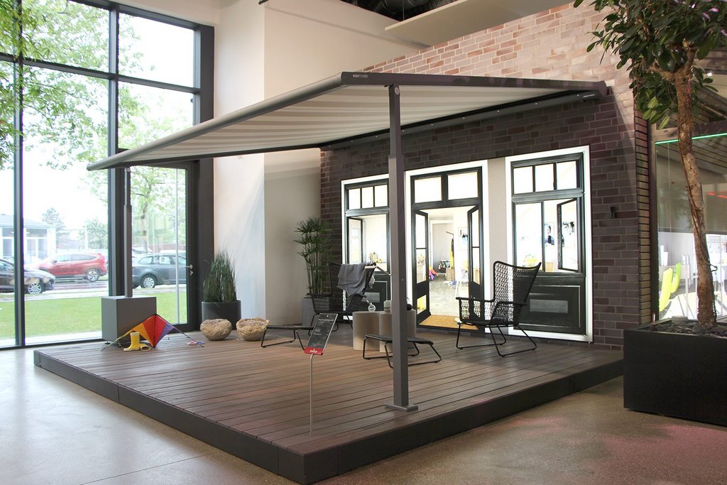 Terrassensituatie met een overkapping, glazen wanden en verschillende meubels in een moderne omgeving. Terrassensituatie met een overkapping, glazen wanden en verschillende meubels in een moderne omgeving.