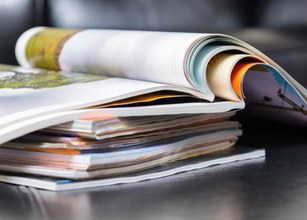 Een stapel tijdschriften met verschillende kleuren, deels opgerold en deels verspreid. 