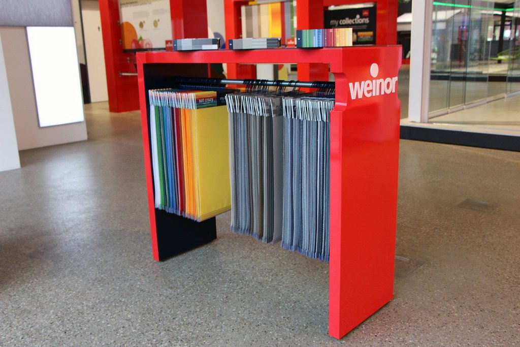 Een rode tafel met verschillende kleuren monsterstoffen aan een rek. Een rode tafel met verschillende kleuren monsterstoffen aan een rek.